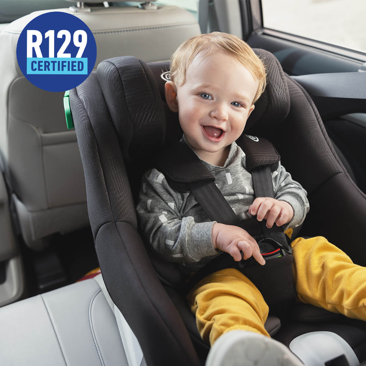 Smiley baby in Graco Extend LX R129 in car with R129 certified logo. 
