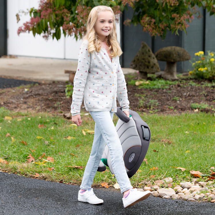 Young girl walking and holding Graco EverSure Lite in one hand