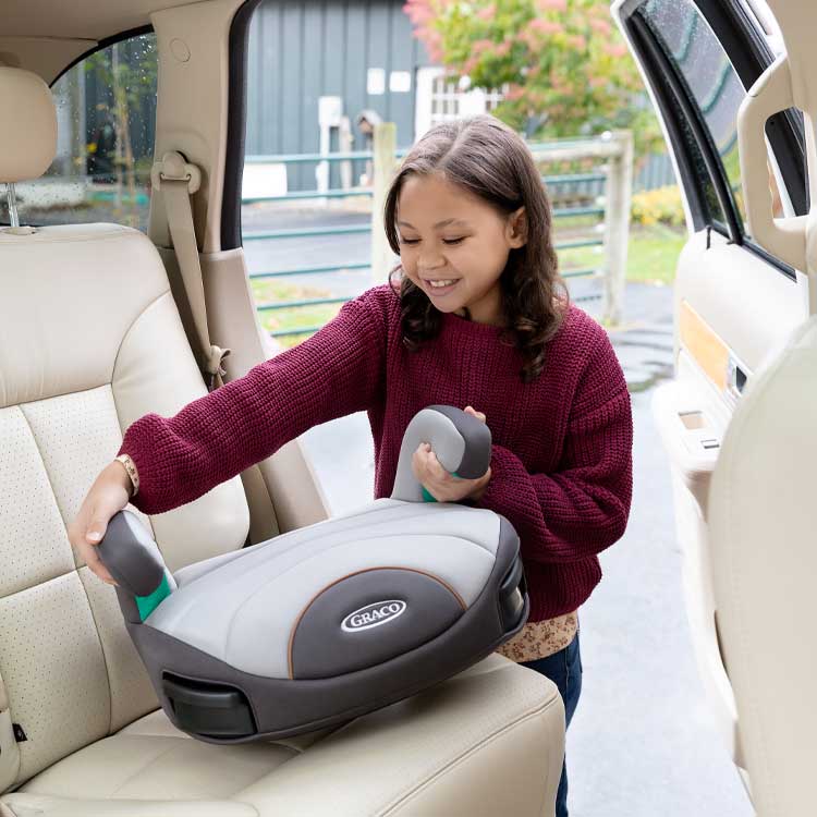 Young girl placing Graco EverSure Lite car seat in the car