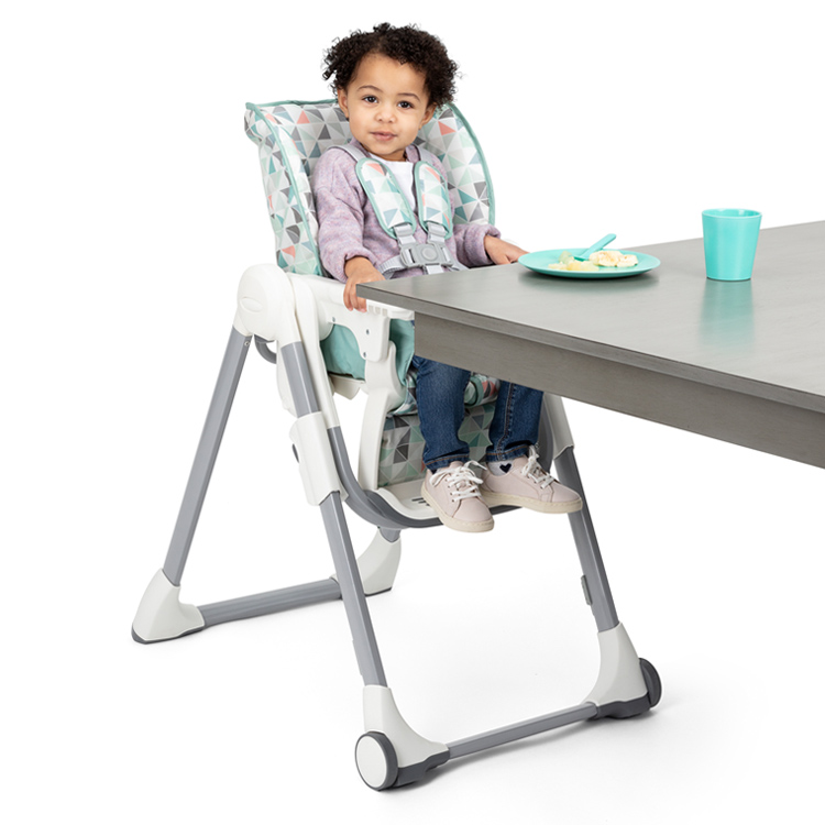 Bambino piccolo seduto ad un tavolo nel seggiolone Swift Fold di Graco
