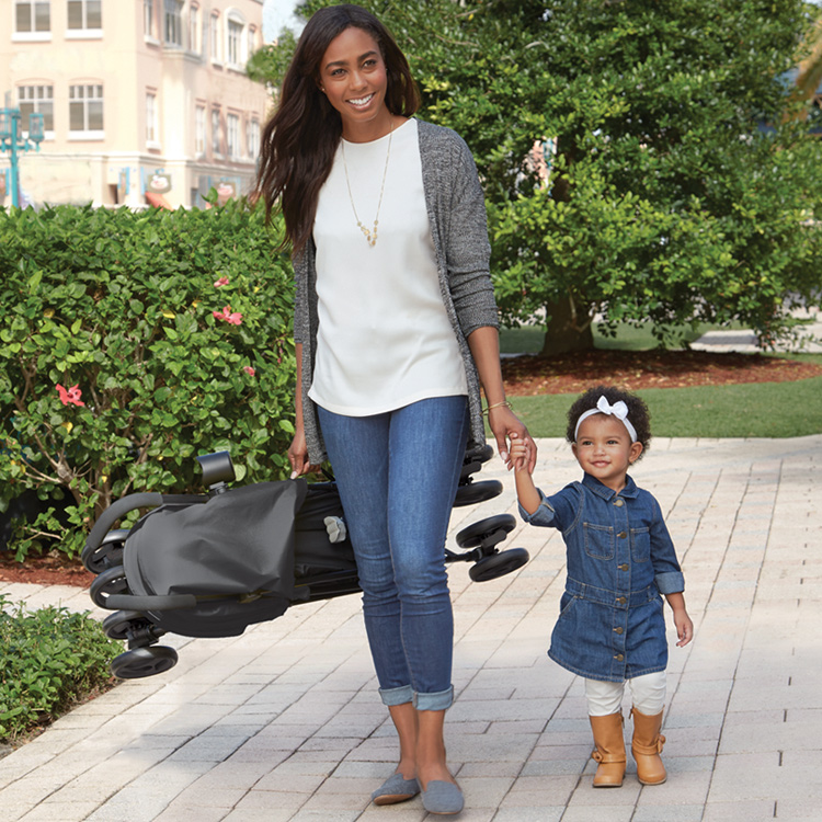 Mum carrying Graco TraveLite™ while walking with her child